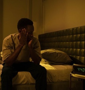 man sitting on bed looking at clock